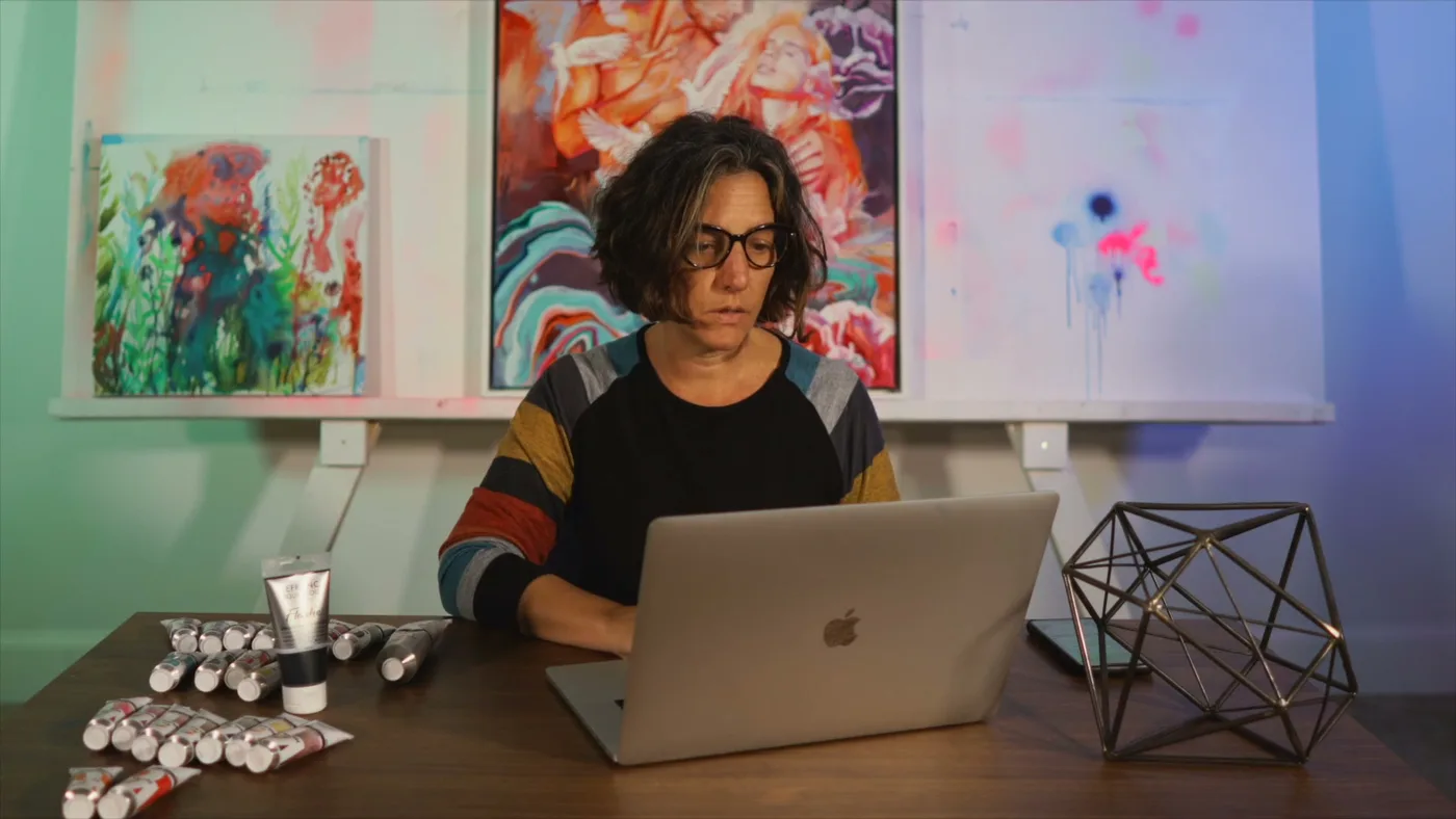 An artist building a painting reference on a laptop in her studio