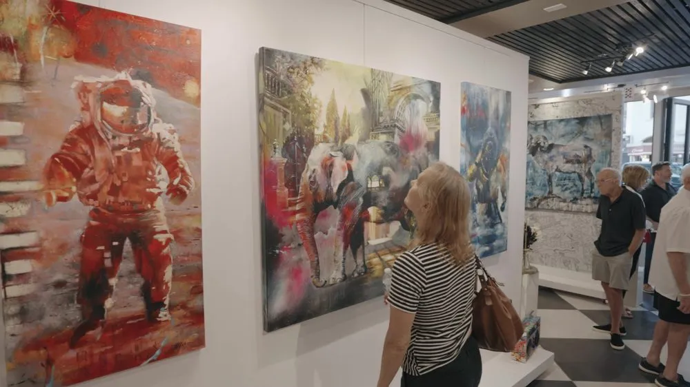 Paintings on the wall of a gallery with a visitor