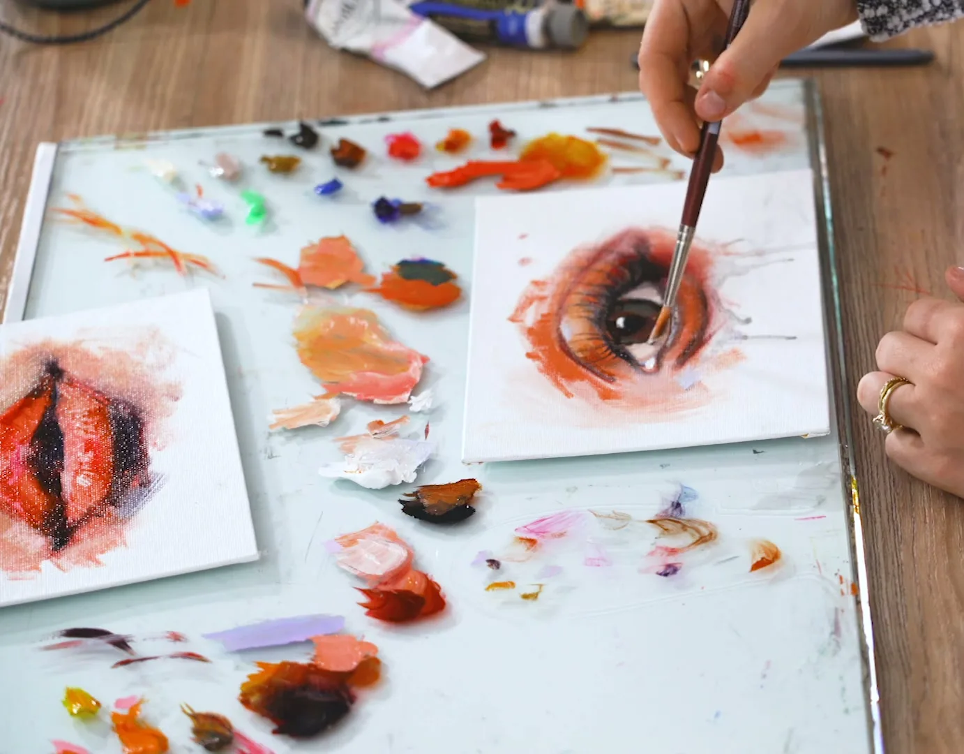A painted study of a single eye in progress beside a glass palette