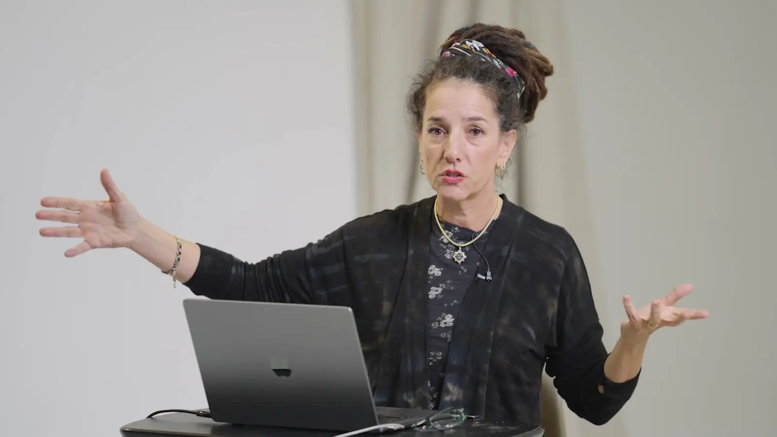 Elli Milan teaching at a standing desk, arms wide, during the Mastery Program lesson on the style spectrum