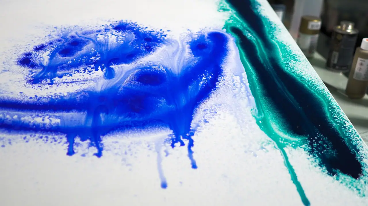 High flow acrylic dripping in blue and green across a canvas