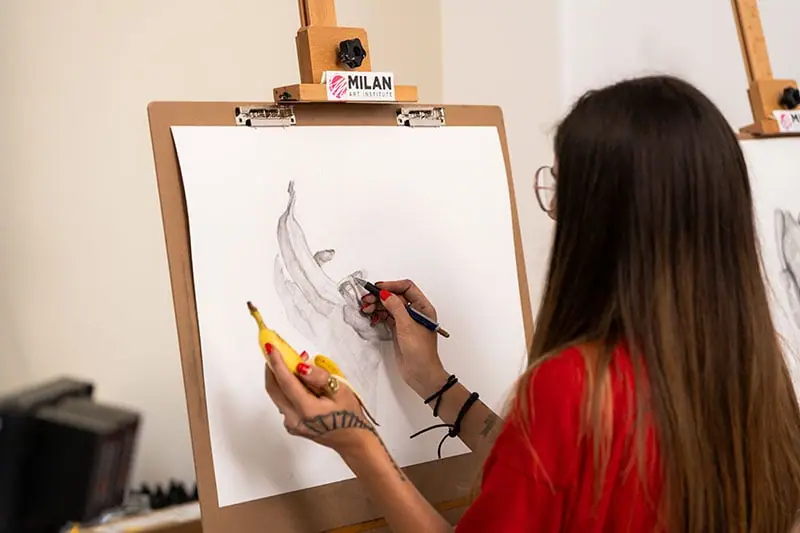 Woman drawing a banana on an easel with a drawing board