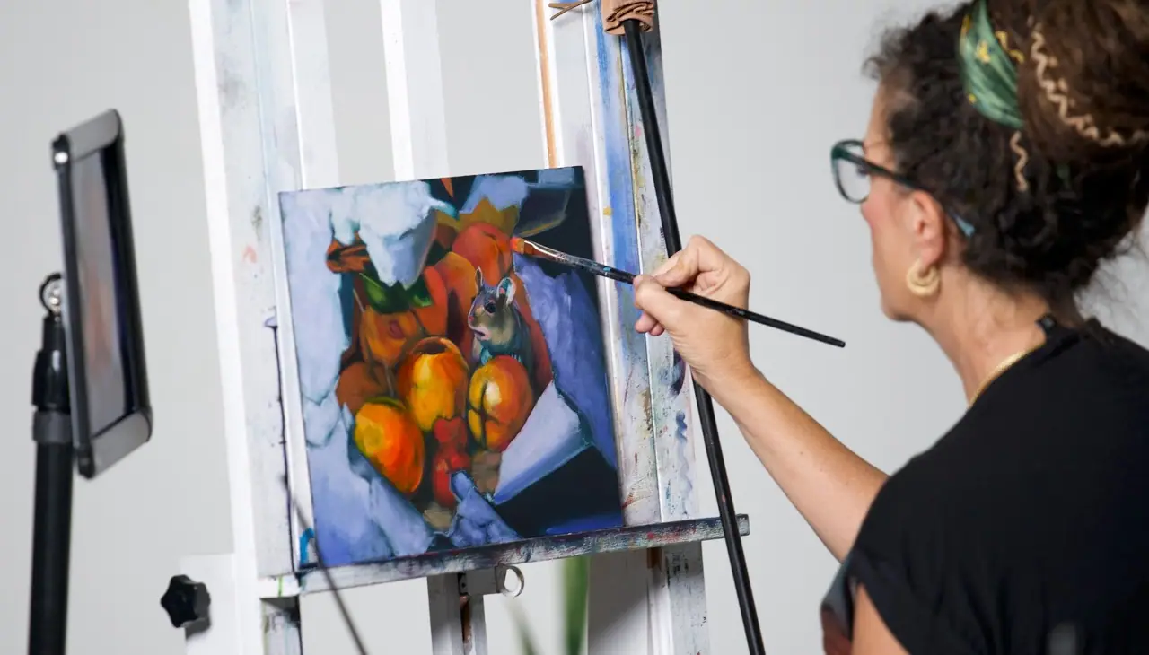 Artist in a black shirt painting a still life with oranges