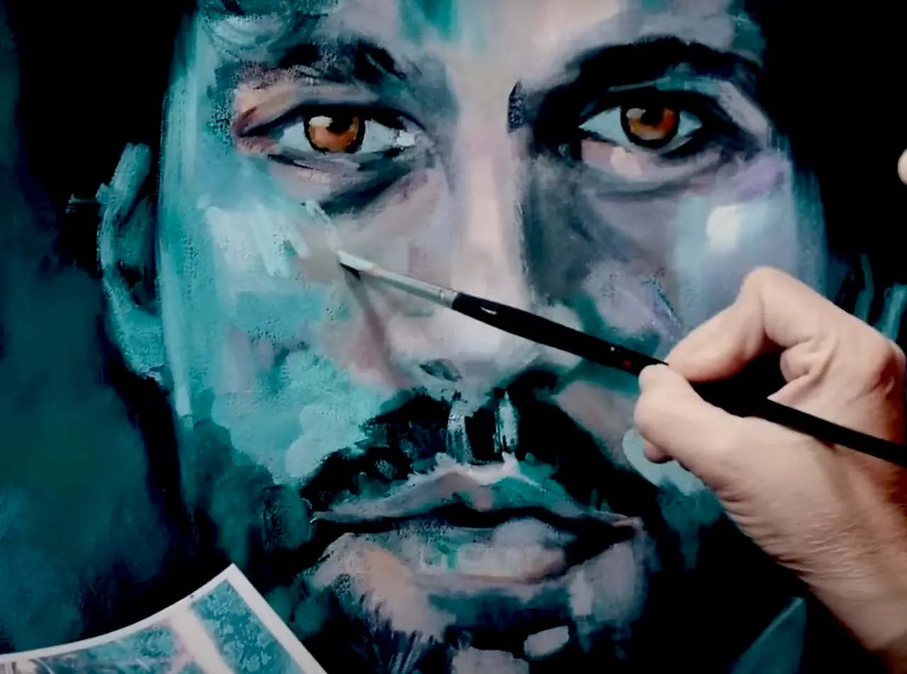 Hand painting a portrait in blue and tan tones with visible brushstrokes