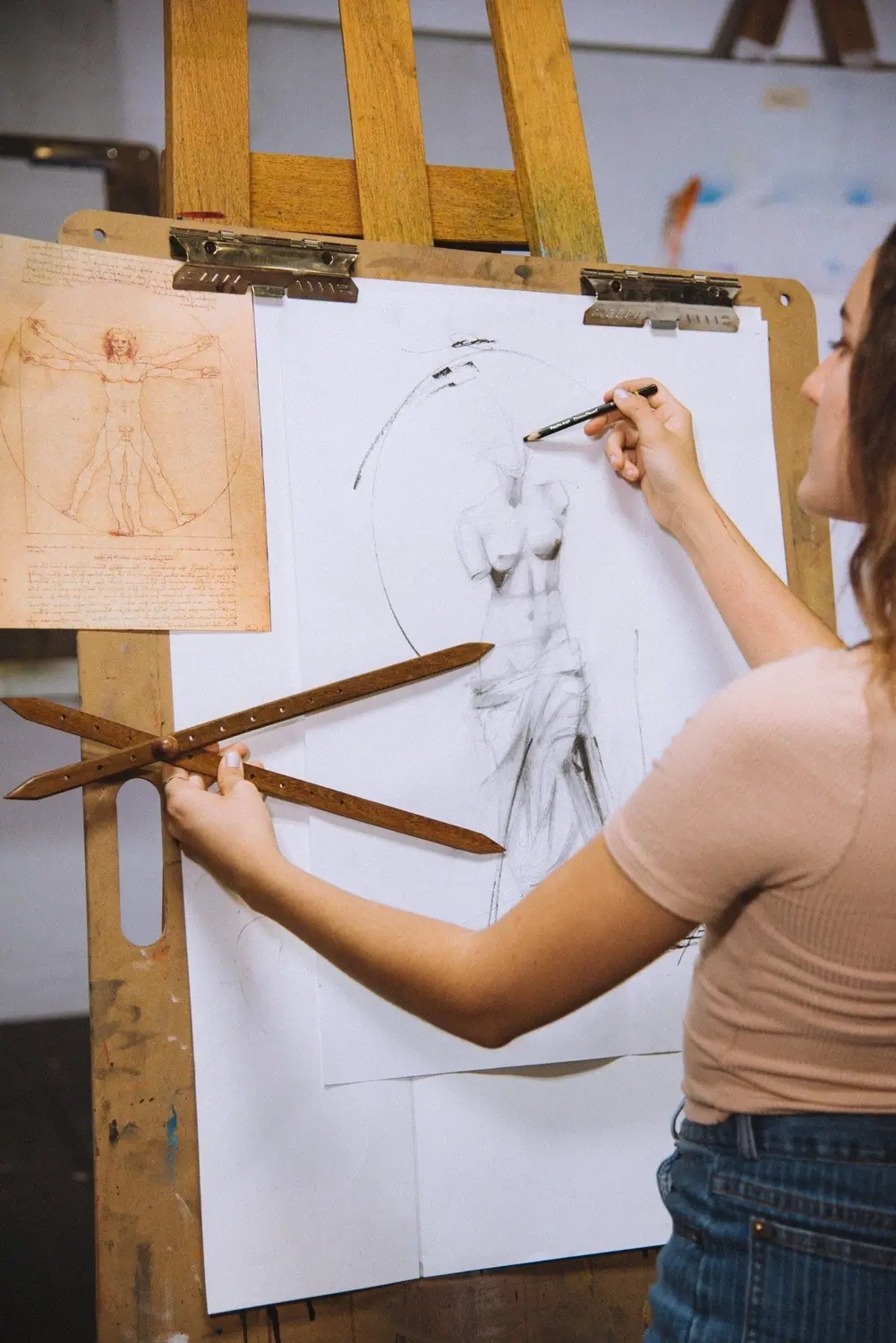 Artist sketching a classical statue from observation on a wood drawing board