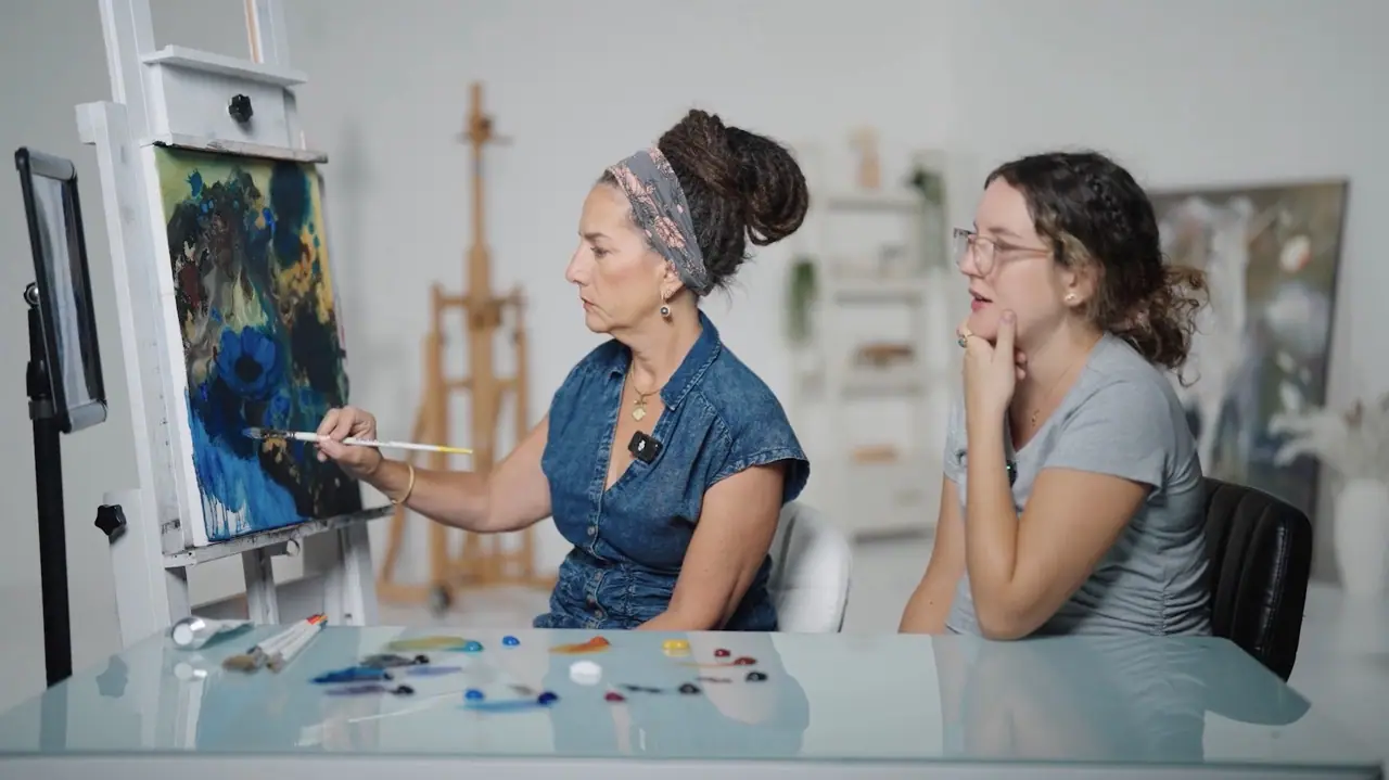 Mentor in blue guiding a student painting at an easel