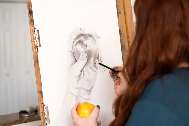 Artist drawing a yellow apple from observation at an upright easel