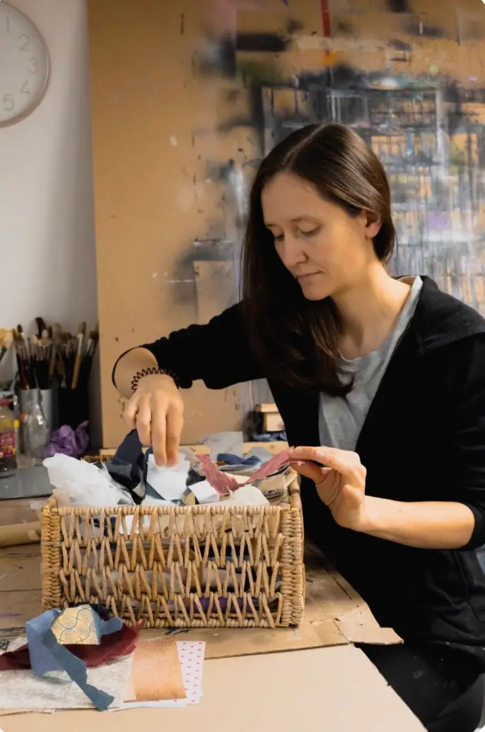Artist sorting papers and supplies into labeled storage in an organized studio space