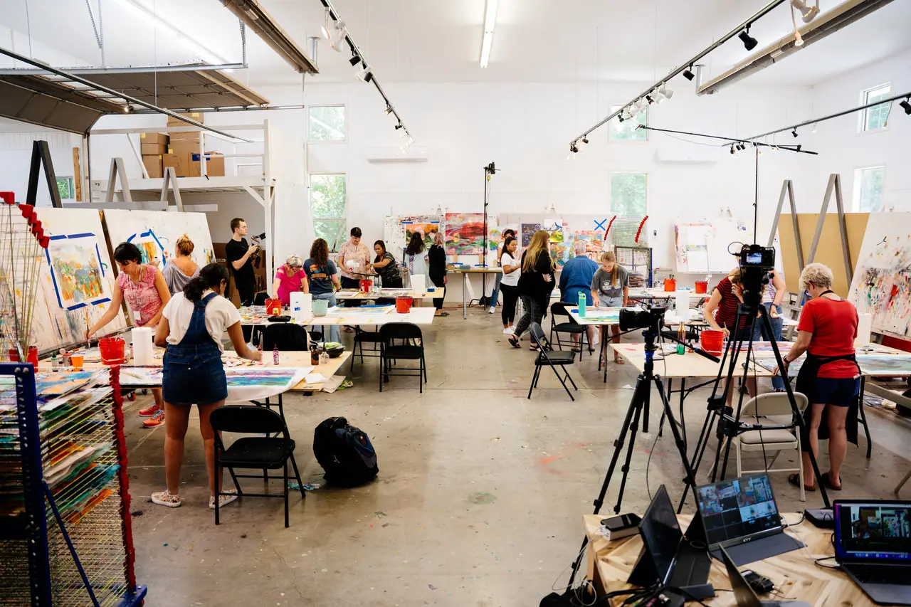 Students painting on tables and easels in an art class