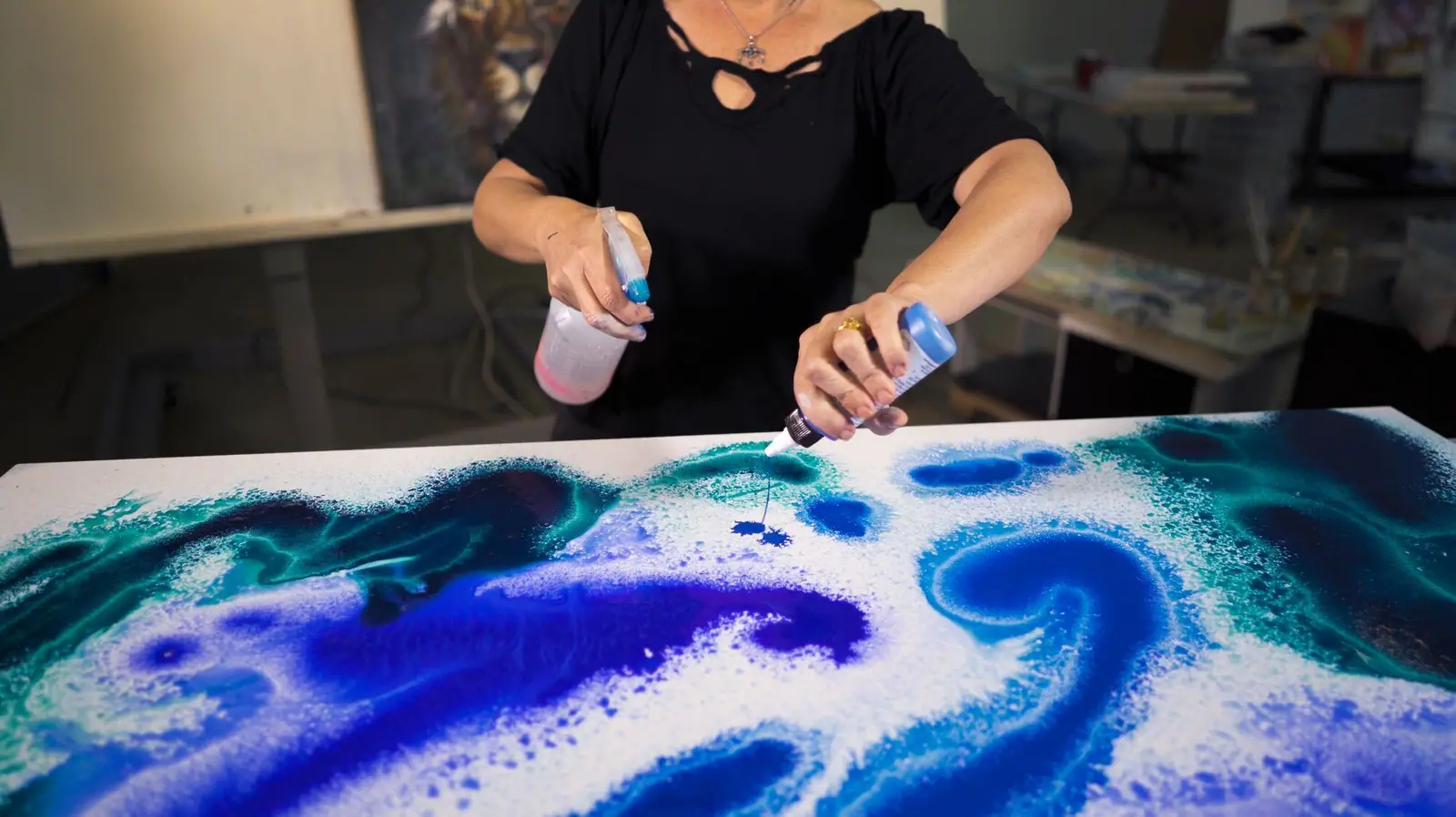 Layered blue high flow acrylic wash with translucent color on canvas