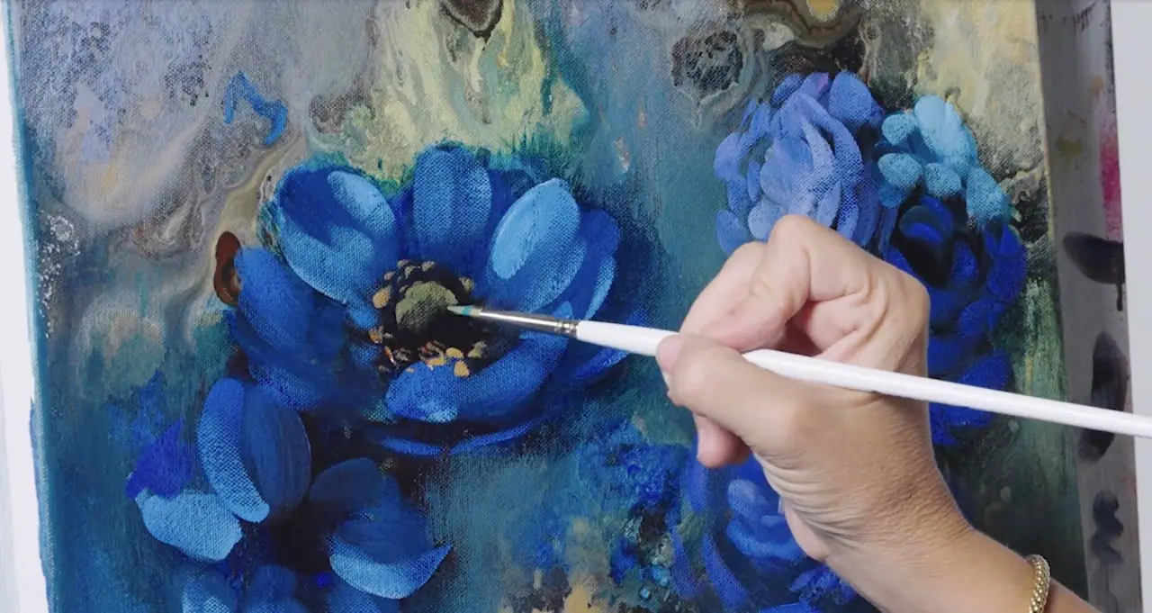 Hand painting blue flowers on canvas with a tan and green center