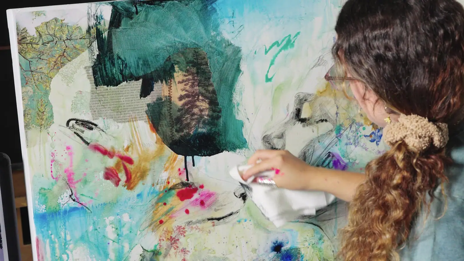 Artist building a green mixed media painting in the studio