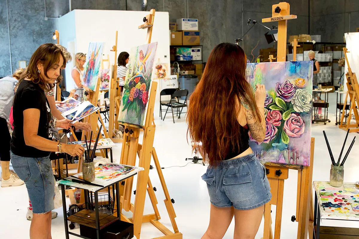 Students painting at easels in a bright workshop classroom