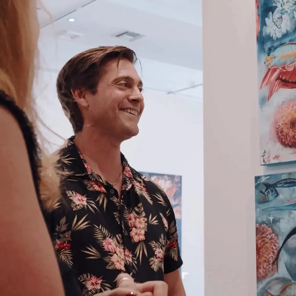 Gallery director standing on a gallery floor talking with a visitor