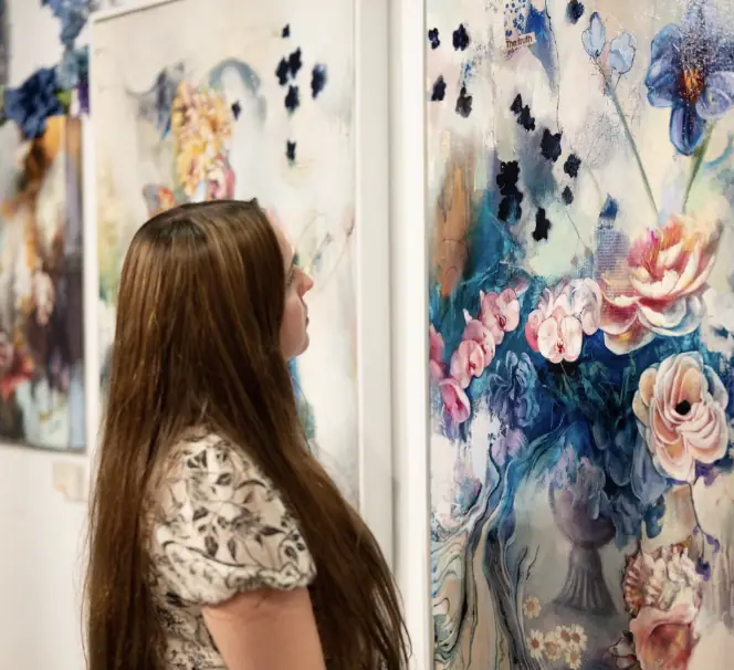 Woman looking closely at a large floral painting