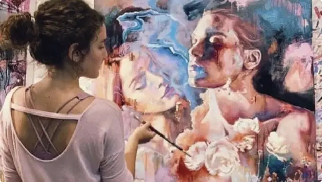 Artist working on an expressive figurative portrait painting in soft blues and reds