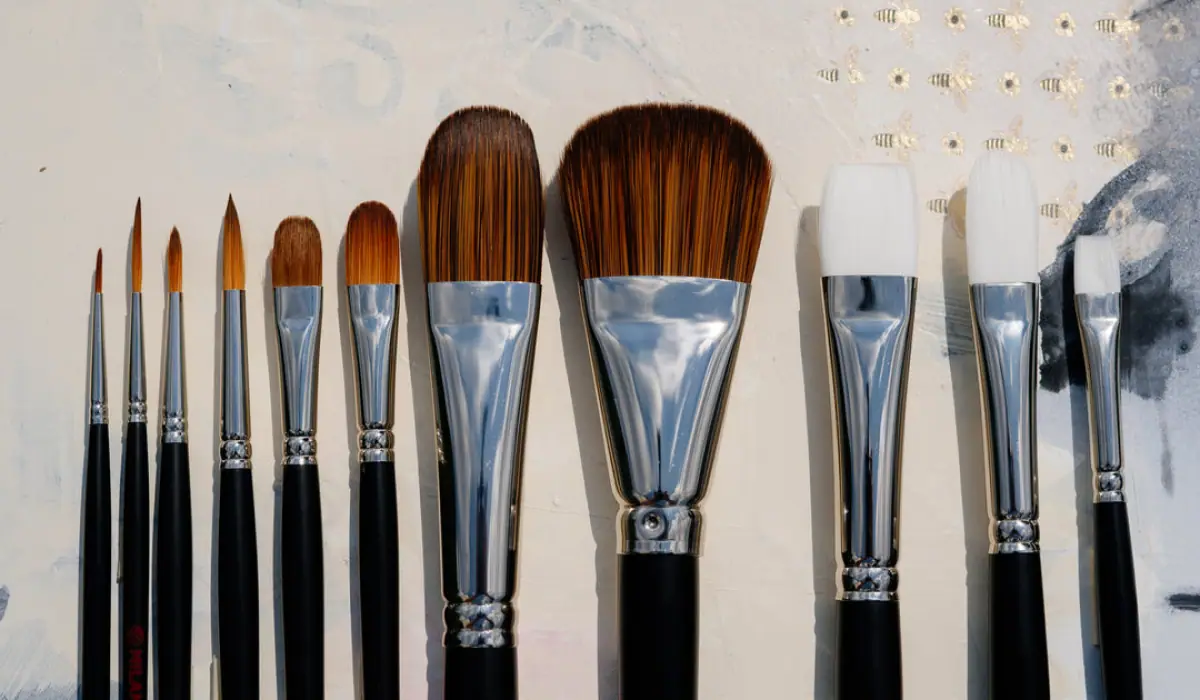 Oil painting brushes with black handles and brown bristles laid out for comparison