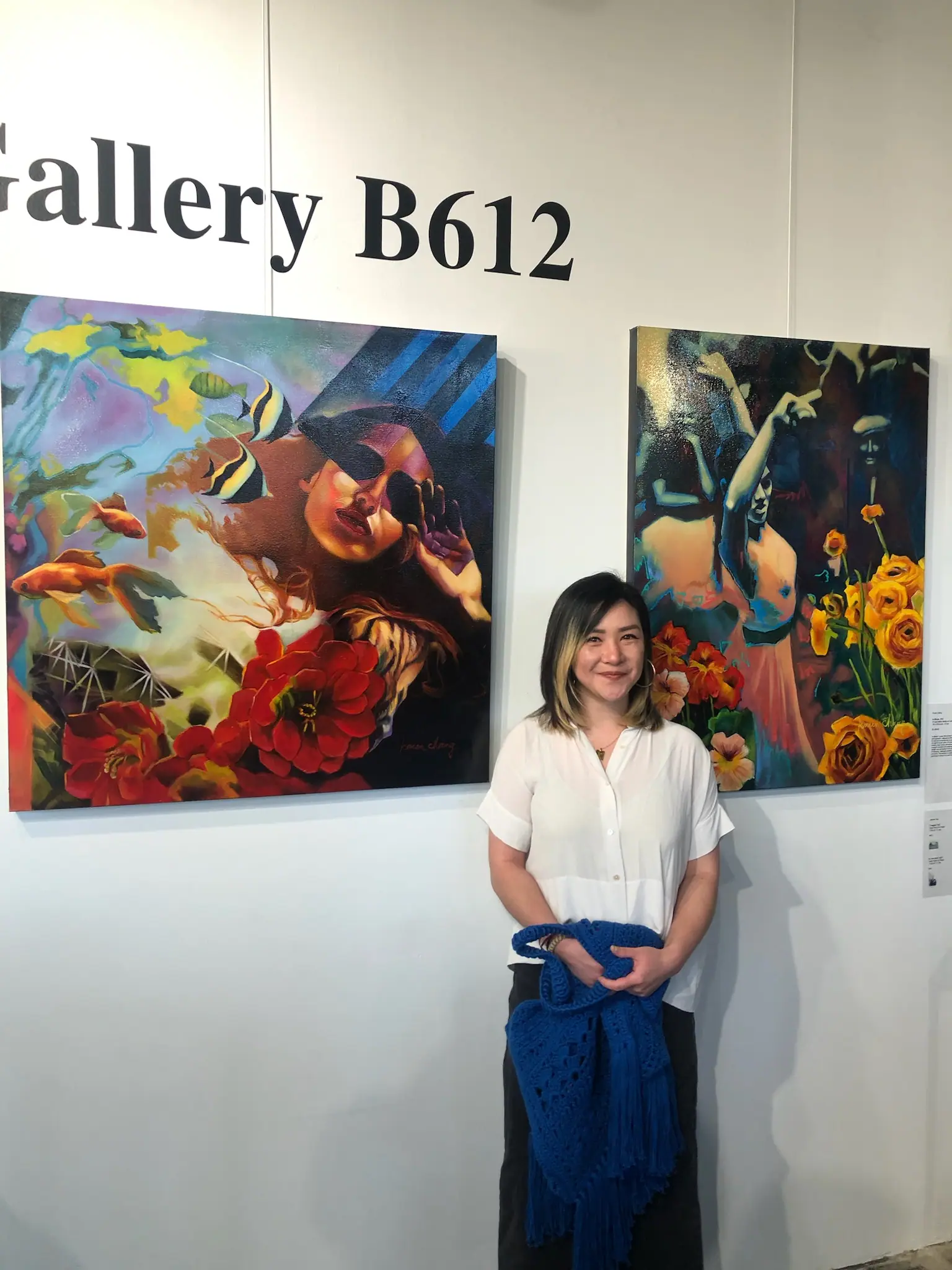 Karen Chang standing in her studio beside one of her portrait paintings