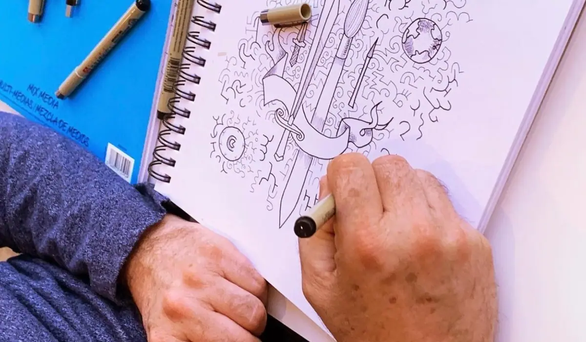 An open sketchbook and pencils set up to draw a busy outdoor Christmas market stall on a cold day
