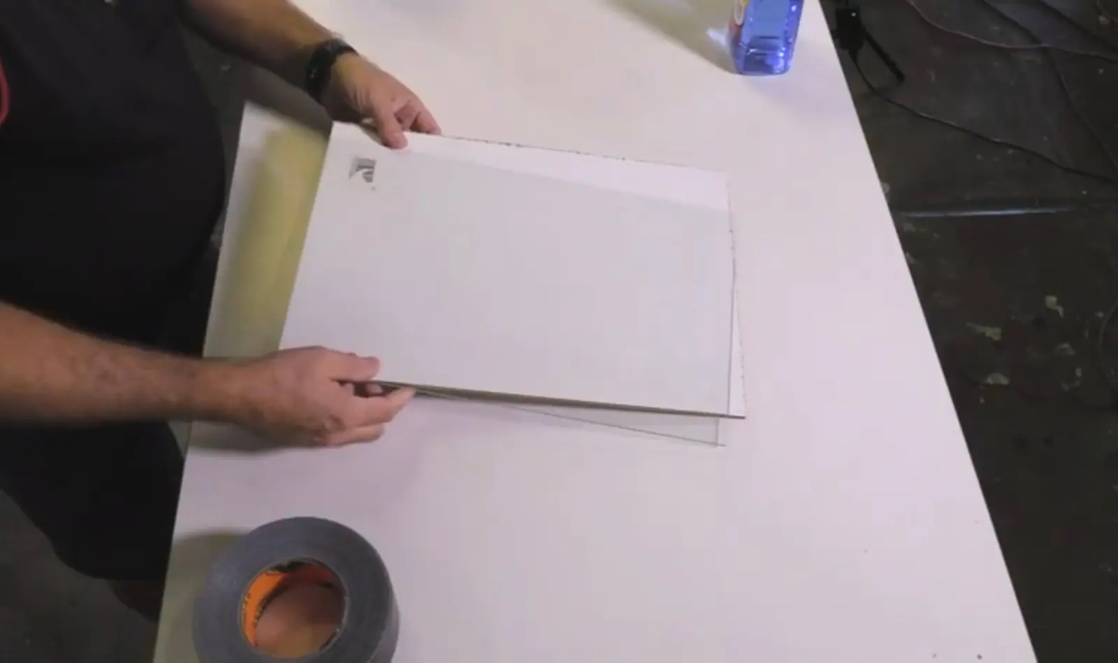 Two hands holding a clear piece of glass to build a DIY artist paint palette