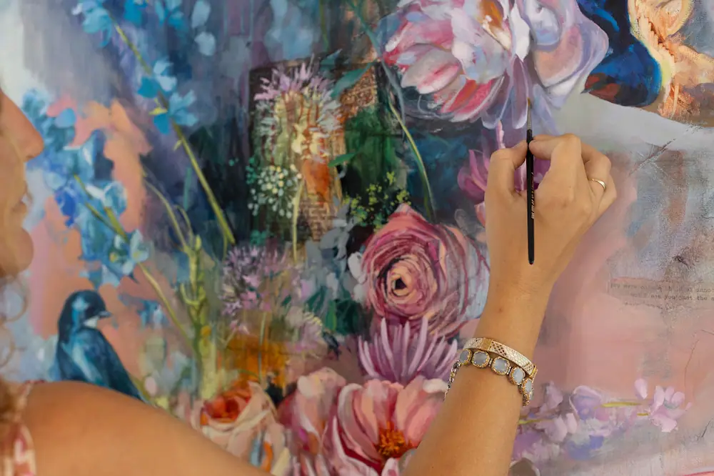 Artist painting a soft floral scene in blue, pink, and peach tones