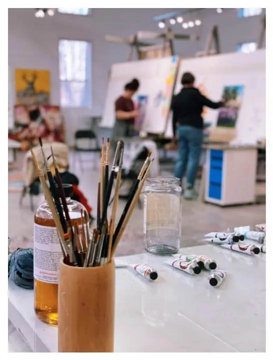 An artist painting at an easel in a studio, building the daily habit that takes a hobbyist toward professional work