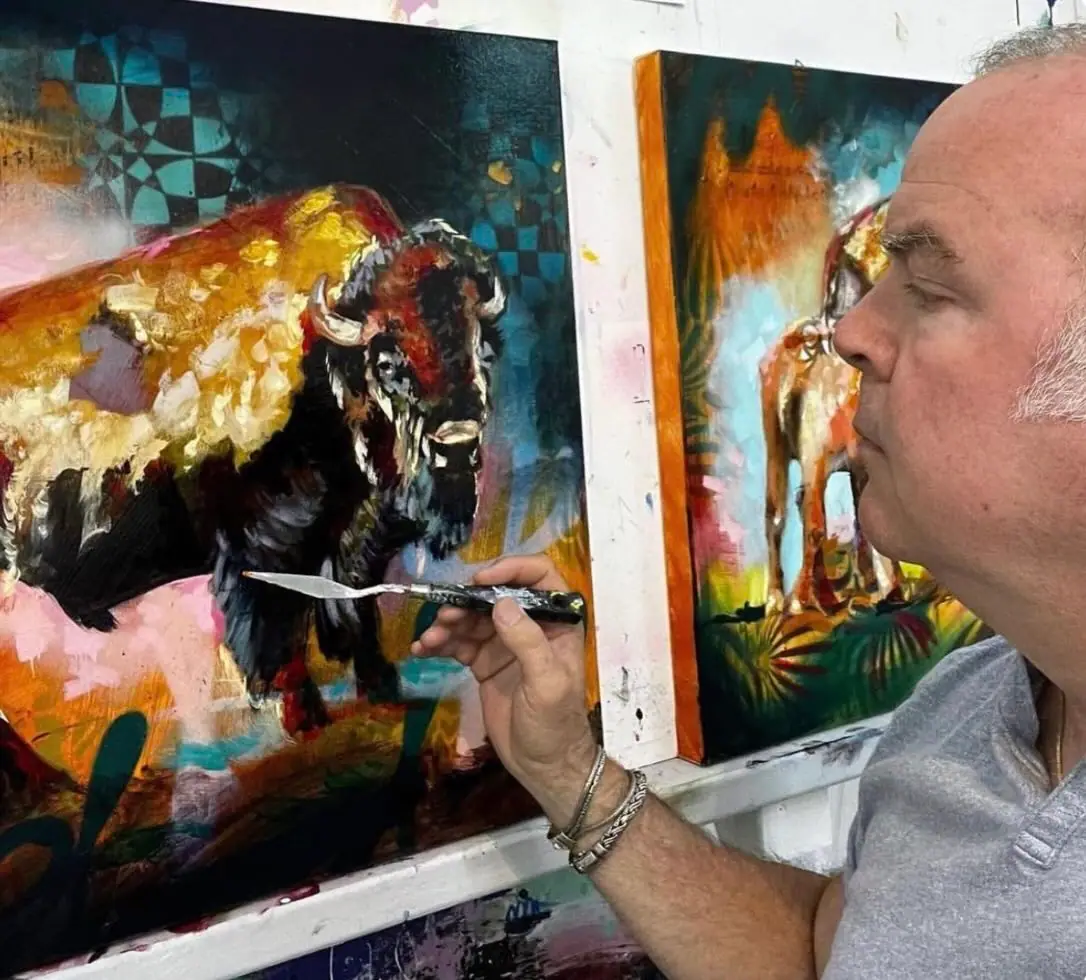 John Milan applying thick paint to a canvas with a palette knife