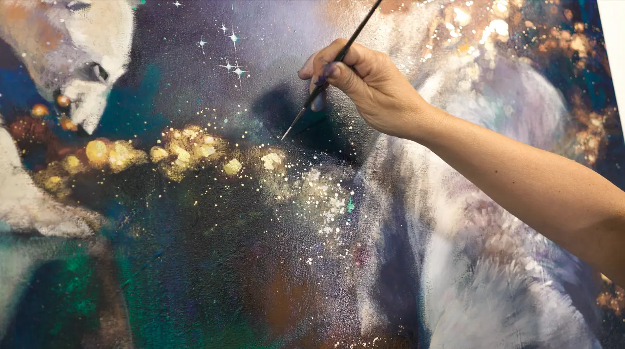 Hand painting a polar bear in glowing purple, green, and white on canvas