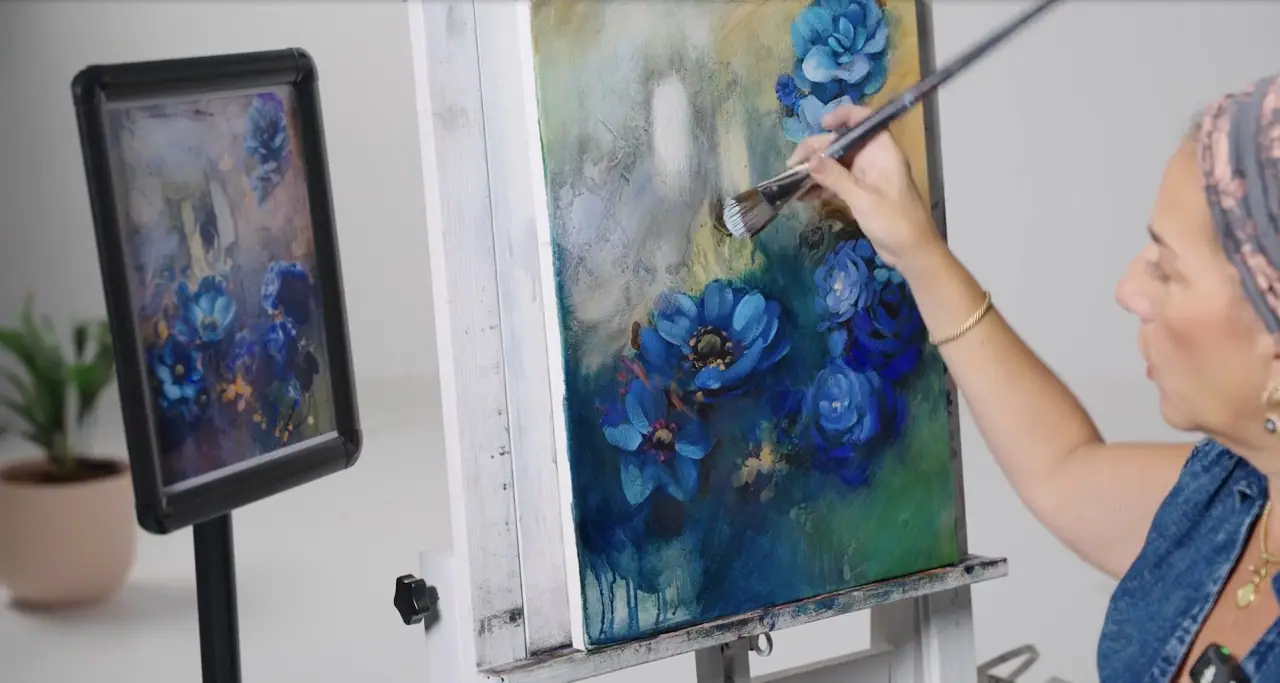 Woman in blue painting blue flowers on a cream and green background on canvas