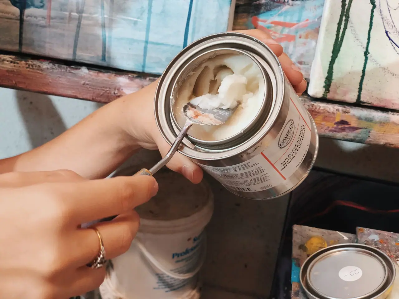 Artist scooping cold wax medium from a jar with a palette knife