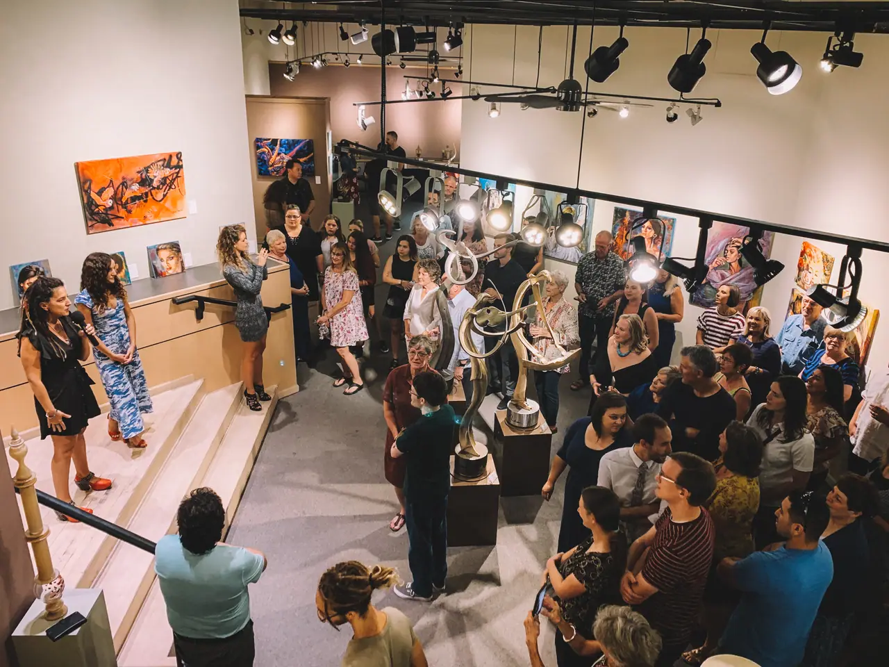 Crowd of people viewing paintings at a busy gallery opening
