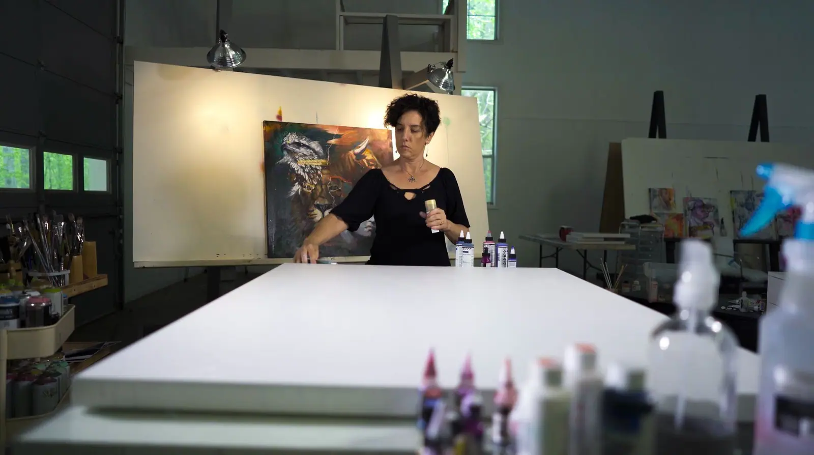 An artist standing at an easel in front of a freshly primed white canvas, ready to begin a painting