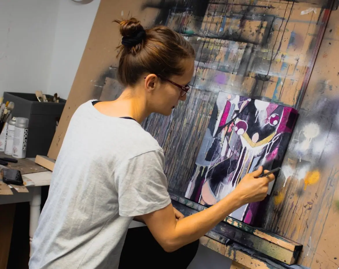 Alina Hermann working drips of paint across an abstract canvas