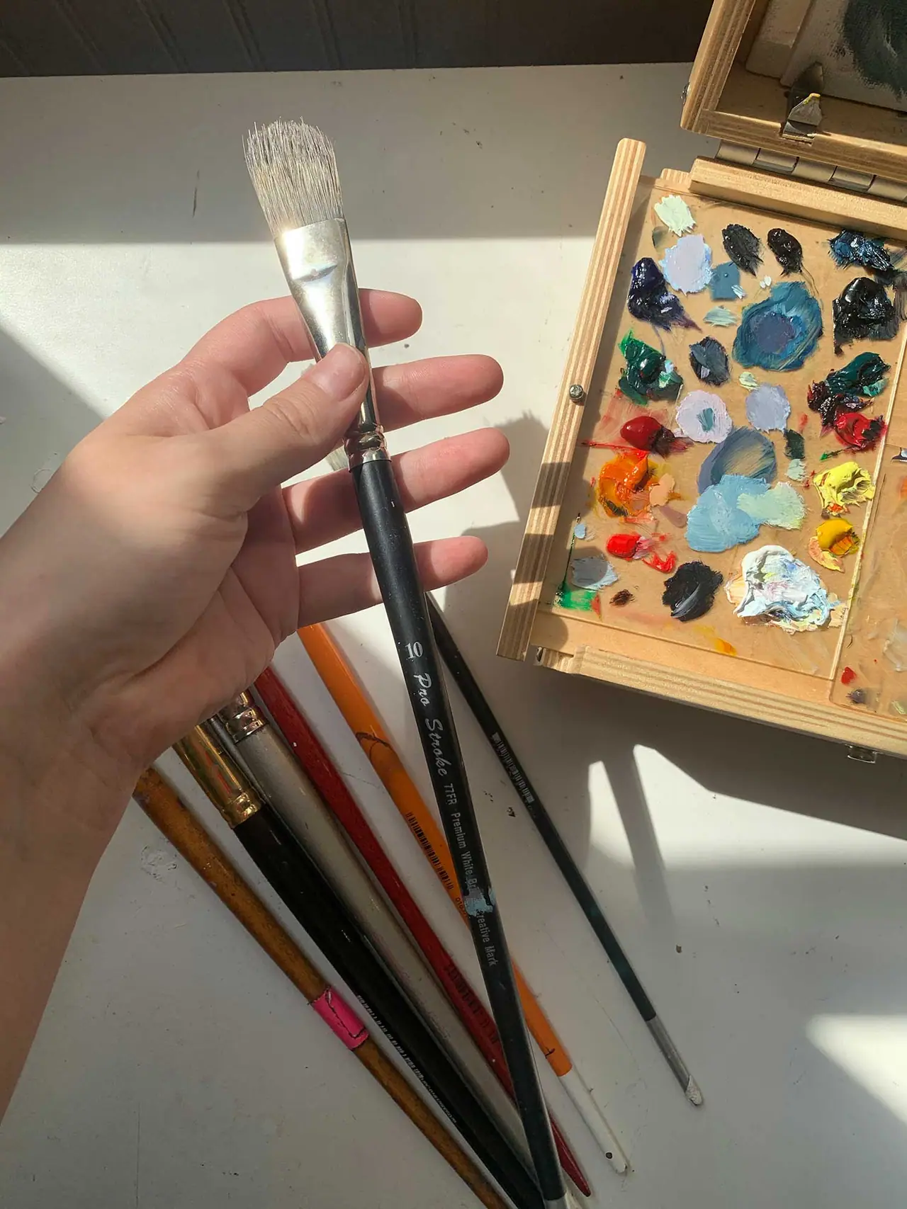 A hand holding a size 10 artist paint brush