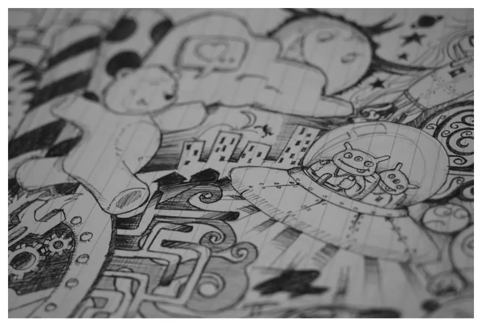 Pen and pencil sketches of faces and shapes filling a page of lined paper