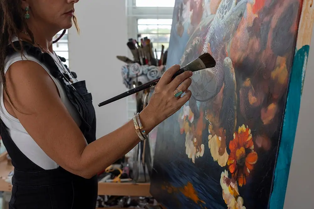 Artist painting with a large brush using bold, high contrast color