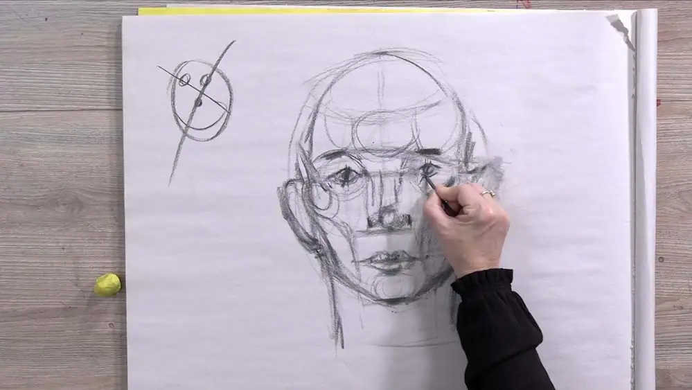 Hand sketching a face on paper using light pencil guidelines to set the proportions