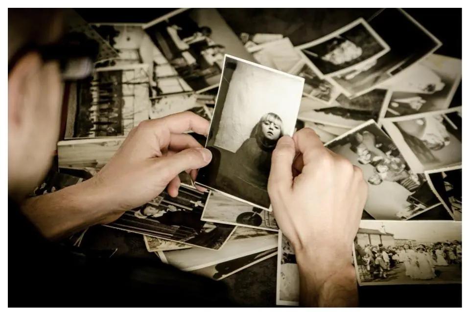 Person holding black and white photographs to compare reference sources for a painting