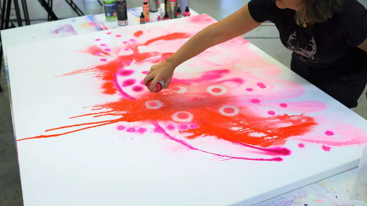 Orange and pink spray paint misted across a canvas