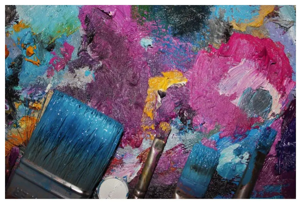 Tubes of artist oil paint in many colors squeezed onto a palette