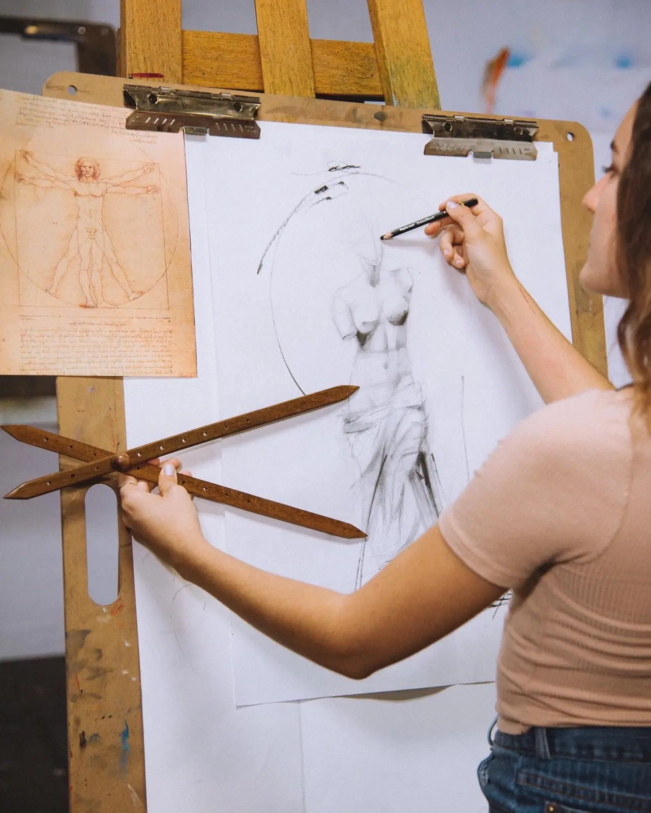 Person standing at a large sheet of paper drawing a figure with a drawing tool
