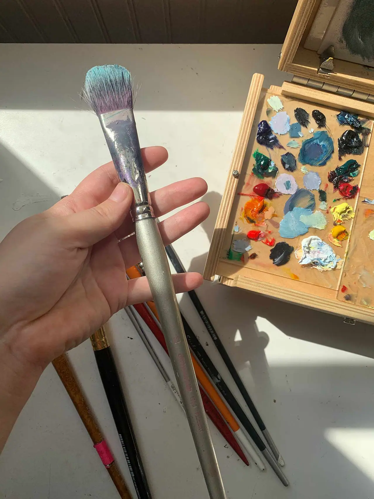 A hand holding a soft blending brush with full bristles