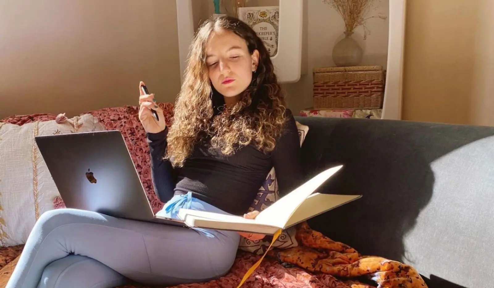 An artist planning her art business in a notebook beside an open laptop
