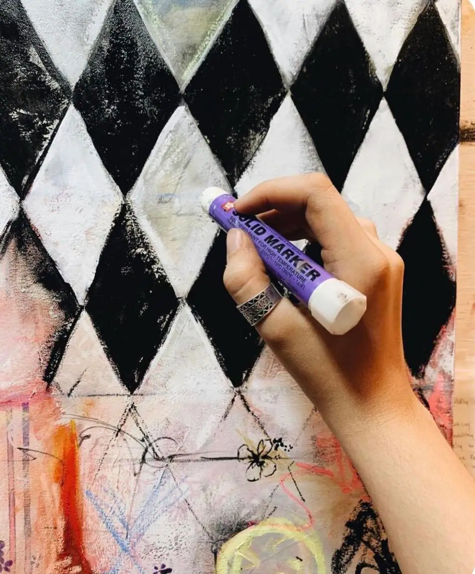 Artist drawing a black and white checker pattern on canvas