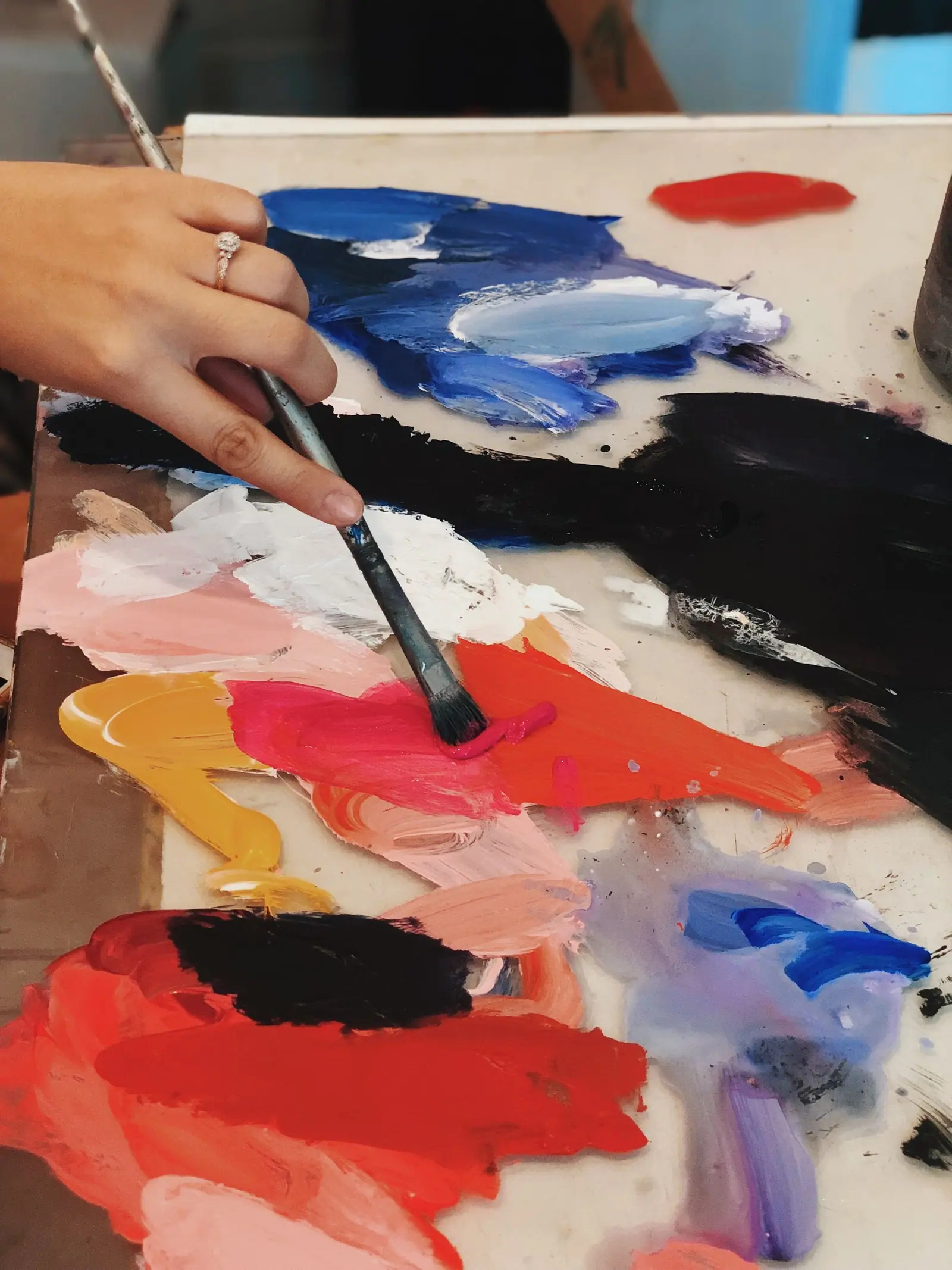 Close view of an artist mixing acrylic paint by hand on a glass palette